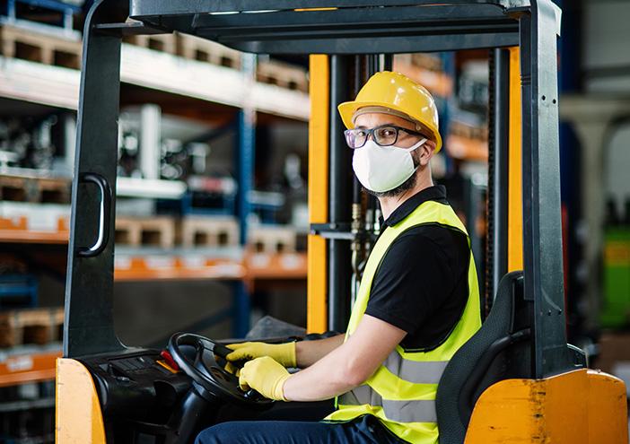 a forklift driver wearing a face mask stops for a photo