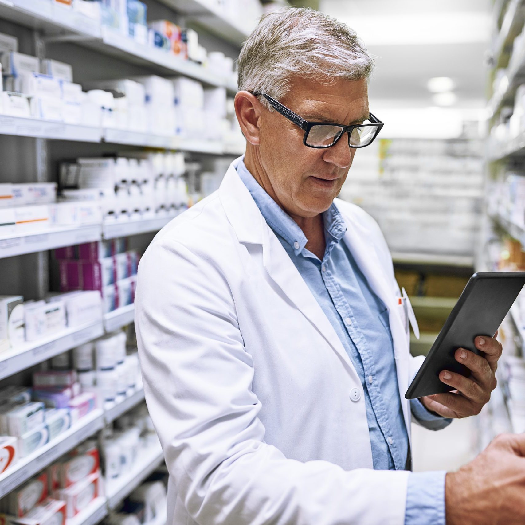 Shot of a focused mature male pharmacist making notes of the medication stock on the shelves in a pharmacy.